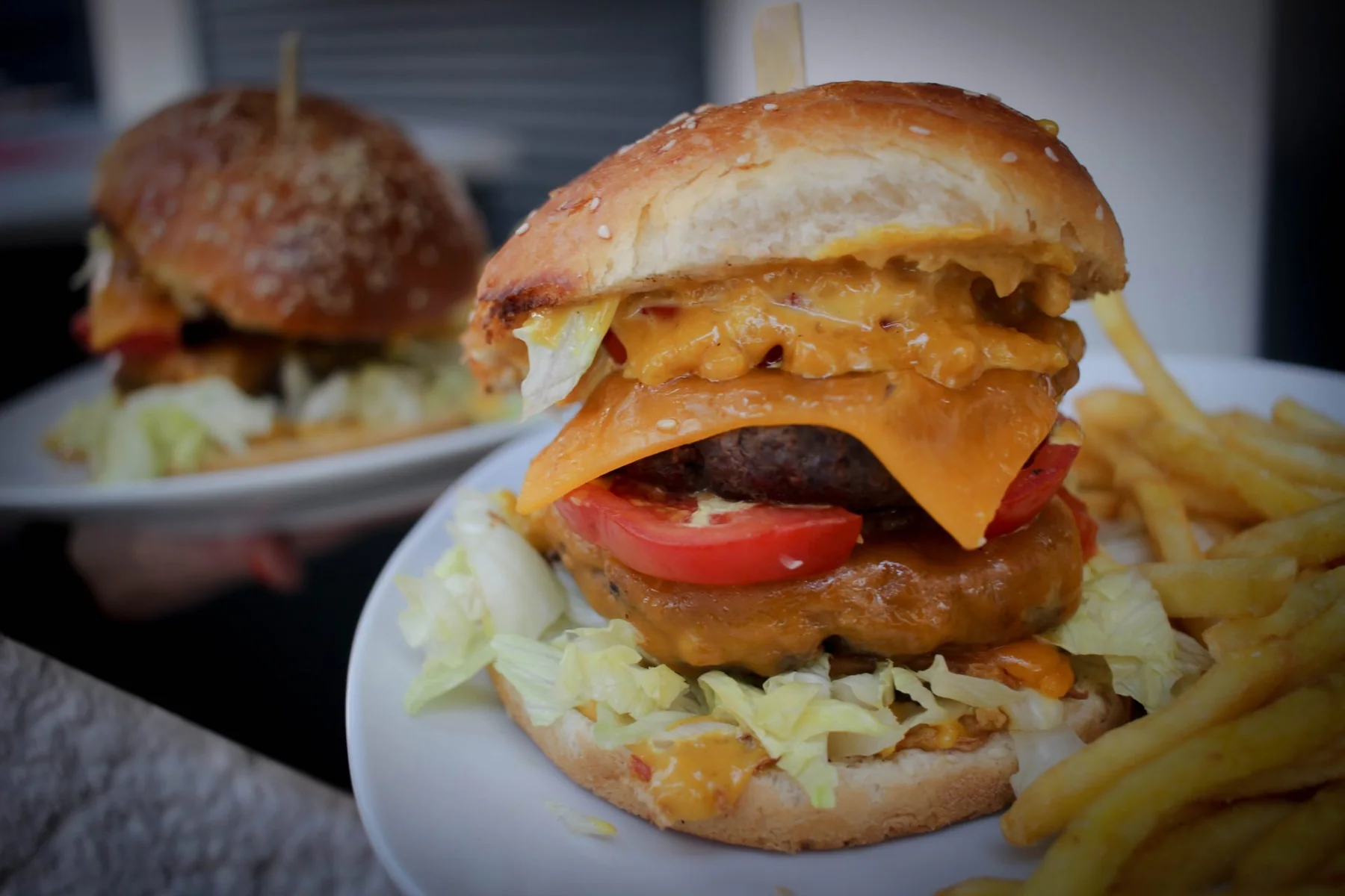 Burger s čedarem, rajčetem a hranolky z nabídky Oázy